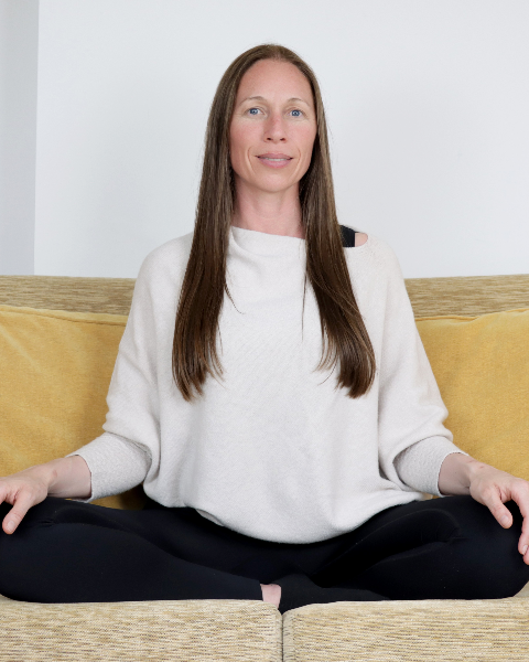 Woman sitting cross-legged on a couch indoors